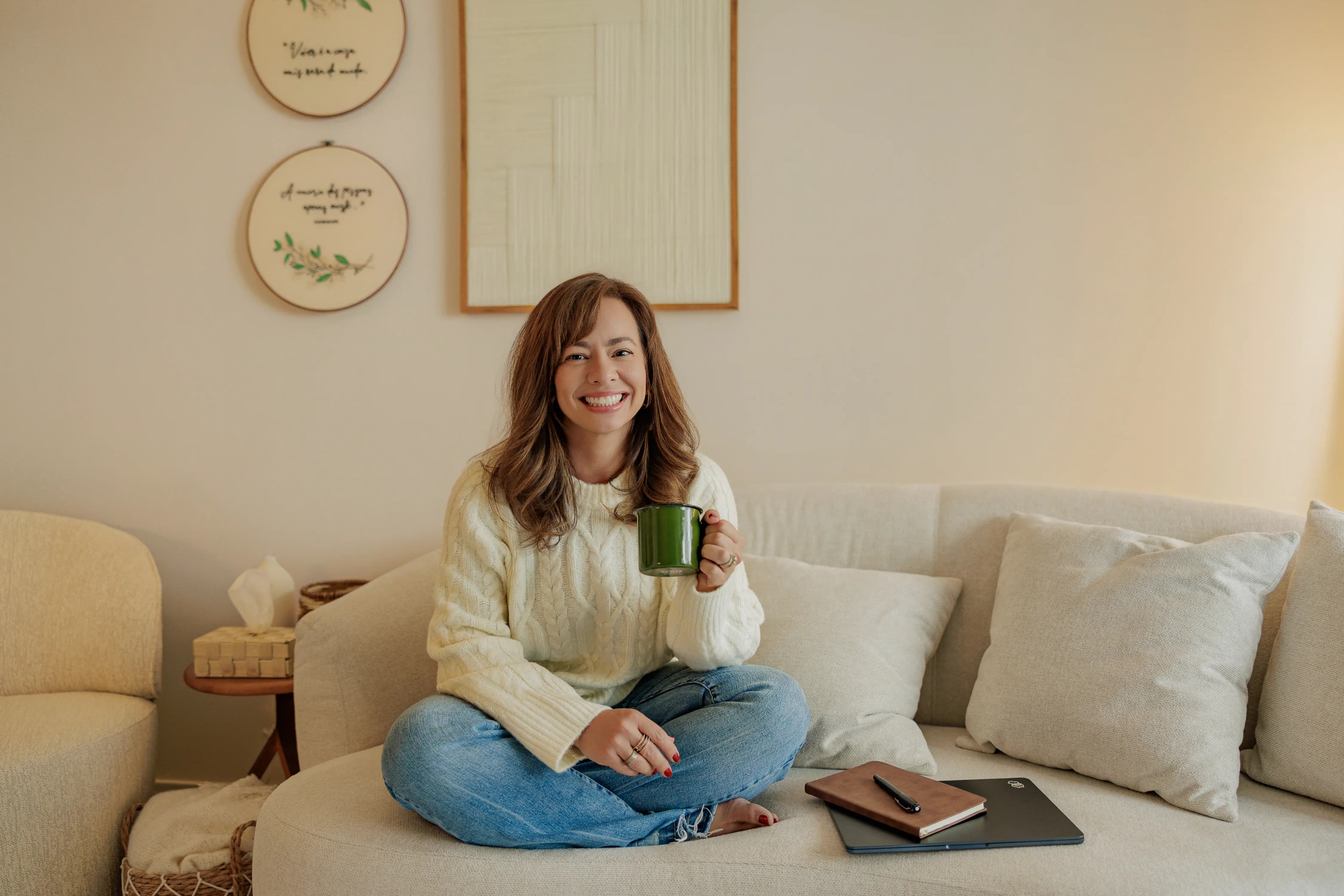 Psicóloga Camila Mazzanti relaxada no sofá com caderno e computador para atendimento presencial