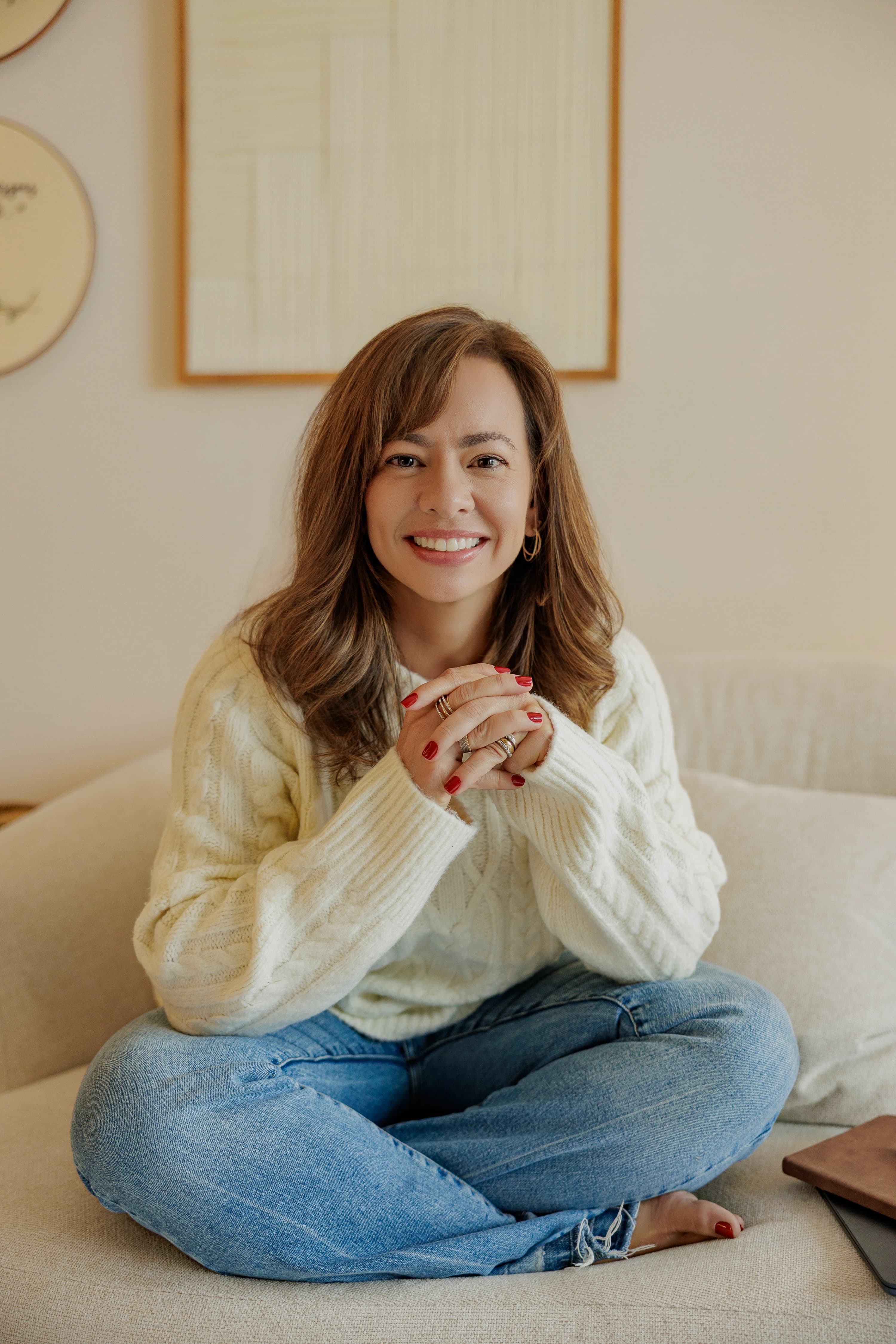 Psicóloga Camila Mazzanti sorrindo sentada em sofá do consultório de psicologia em São Paulo