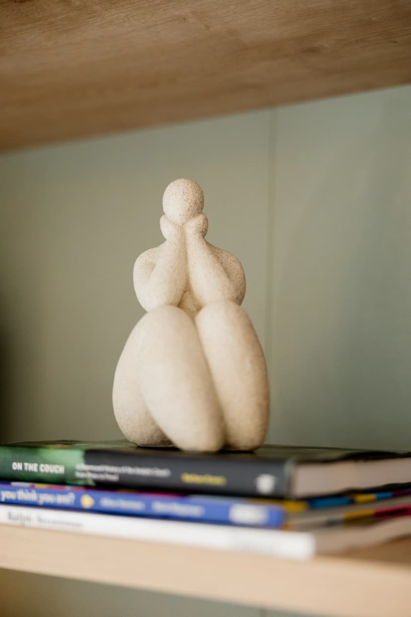 Escultura minimalista branca e livros de psicologia na decoração do consultório