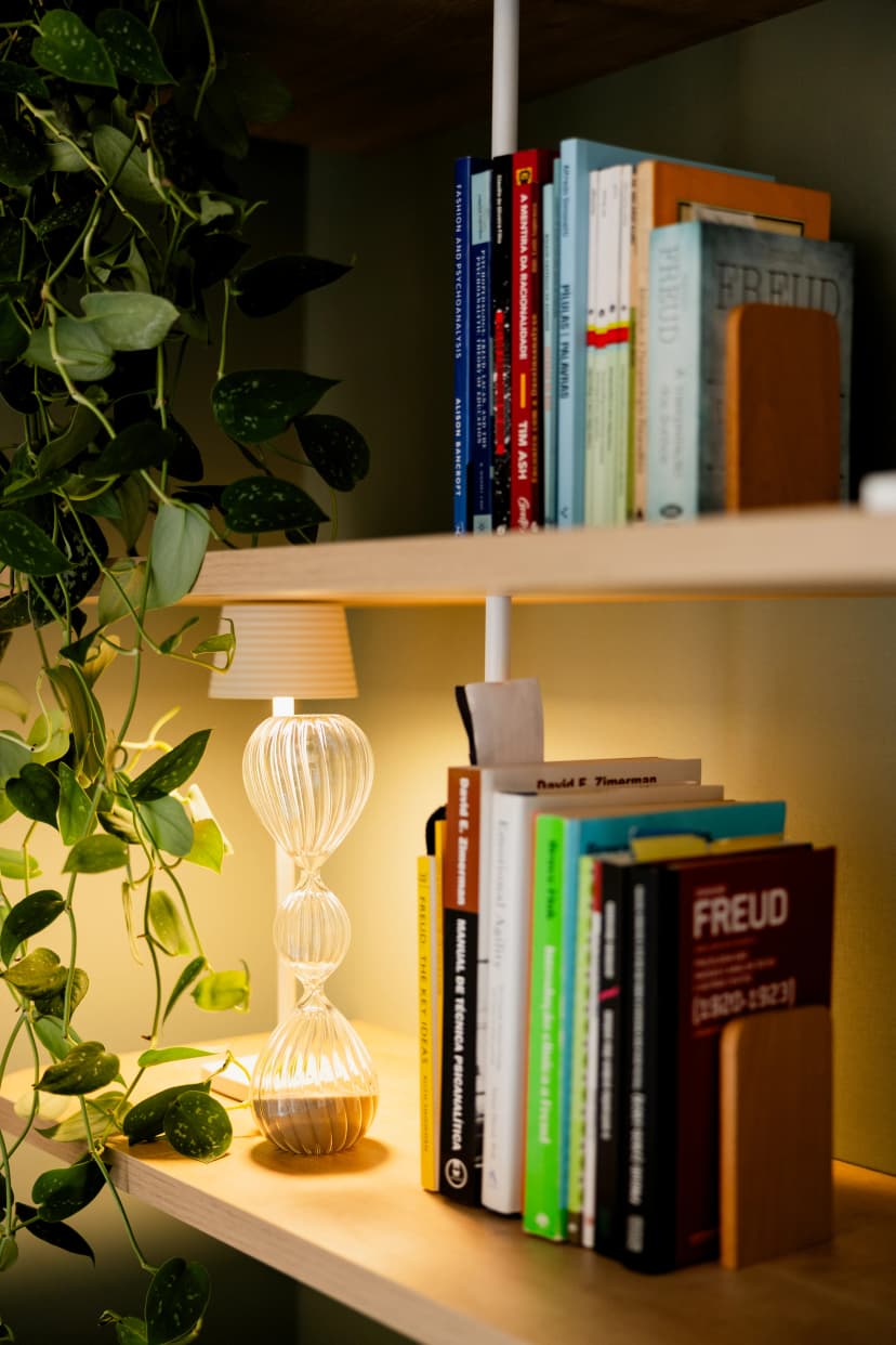 Luminária de vidro texturizado e livros de psicologia na estante decorativa