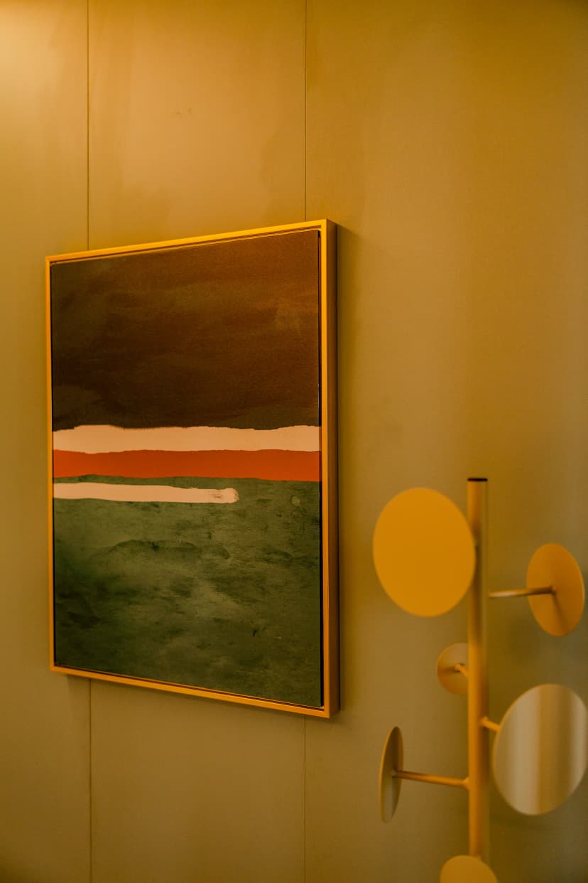 Quadro abstrato e cabideiro amarelo na decoração moderna do consultório